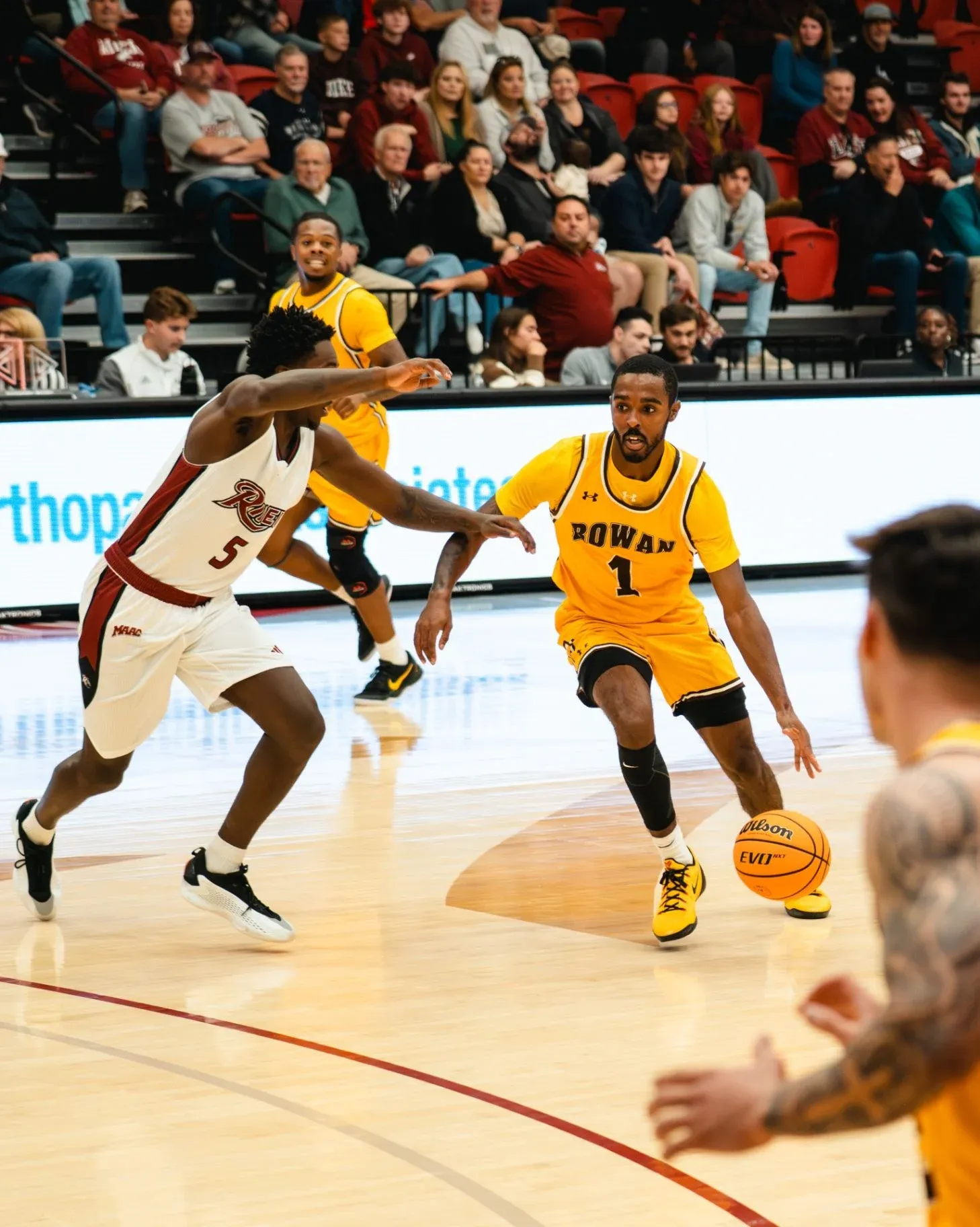 Fareed Burton Jr. driving past a defender in a gold Rowan College number one jersey
