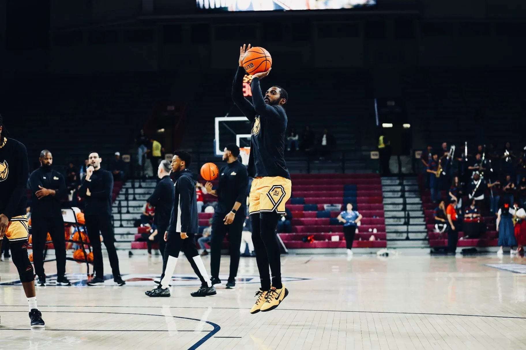 Fareed Burton Jr. rising for a jump shot in a dark arena