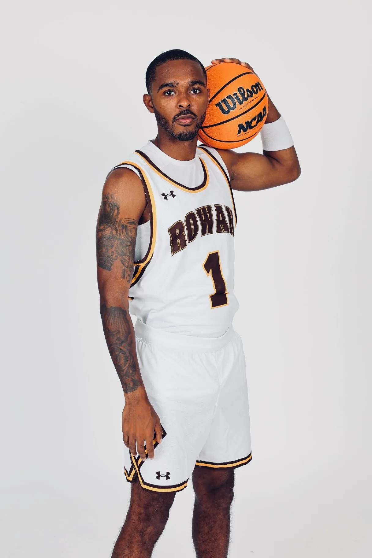 Fareed Burton Jr. in a white Rowan College number one jersey holding a basketball on his shoulder